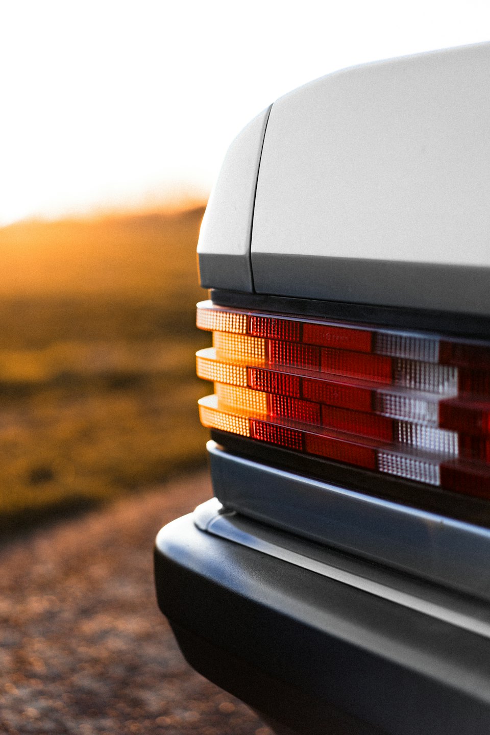 A classic car's red taillight glows at sunset.