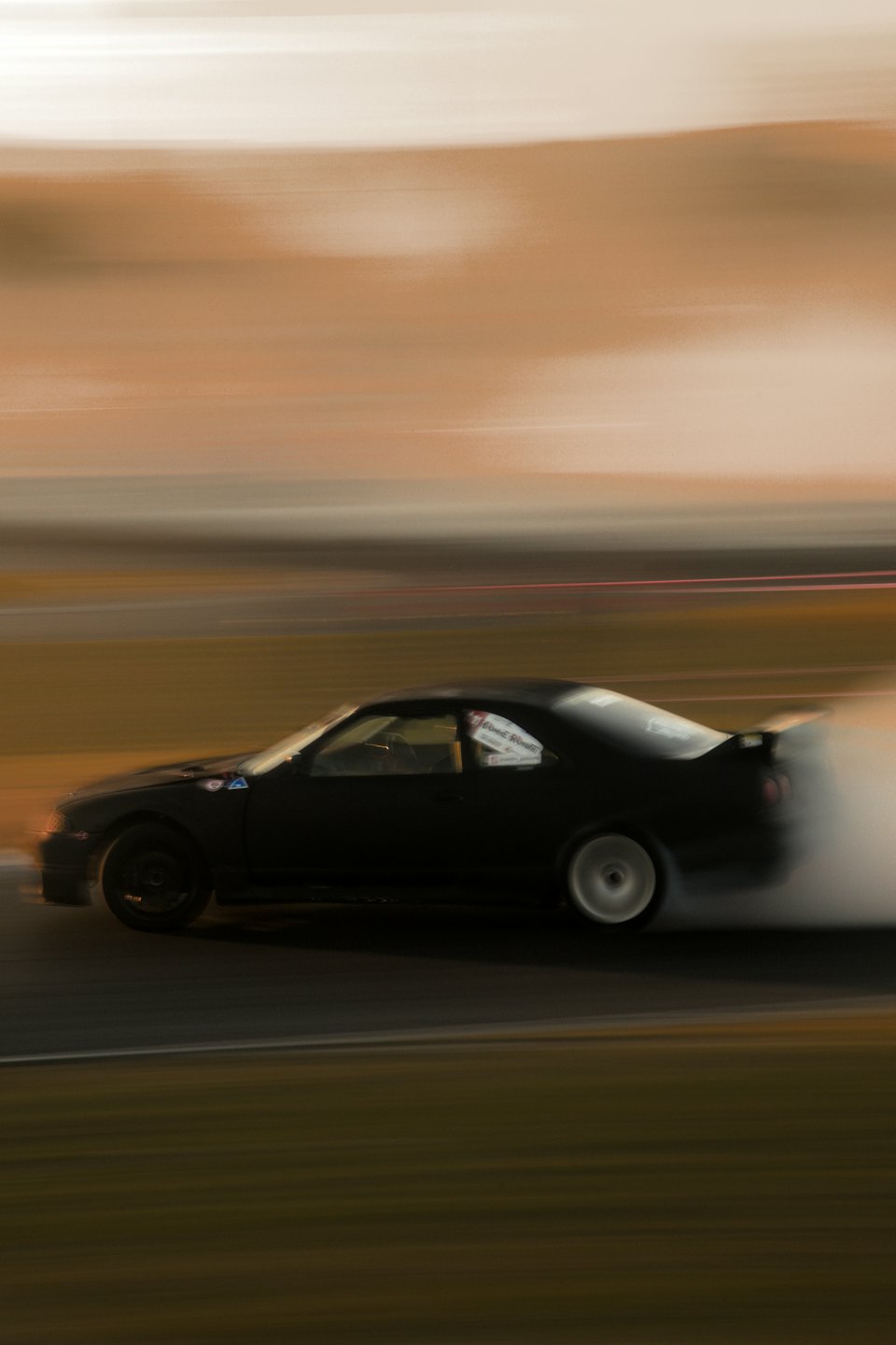 Dark race car drifting and creating smoke on the track.