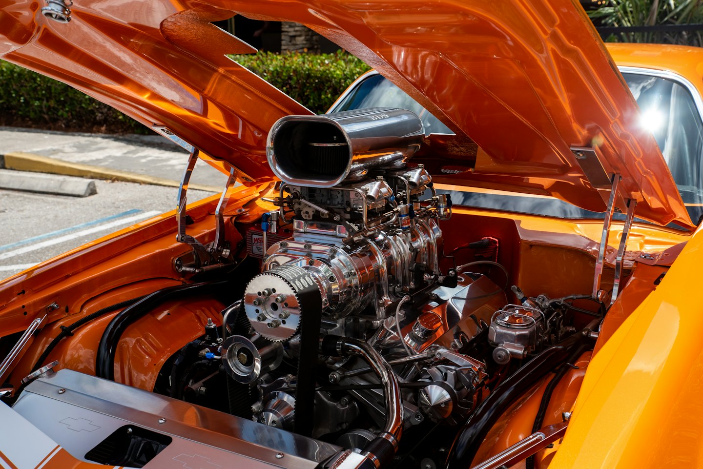 Custom V8 engine with a chrome supercharger inside an orange car.