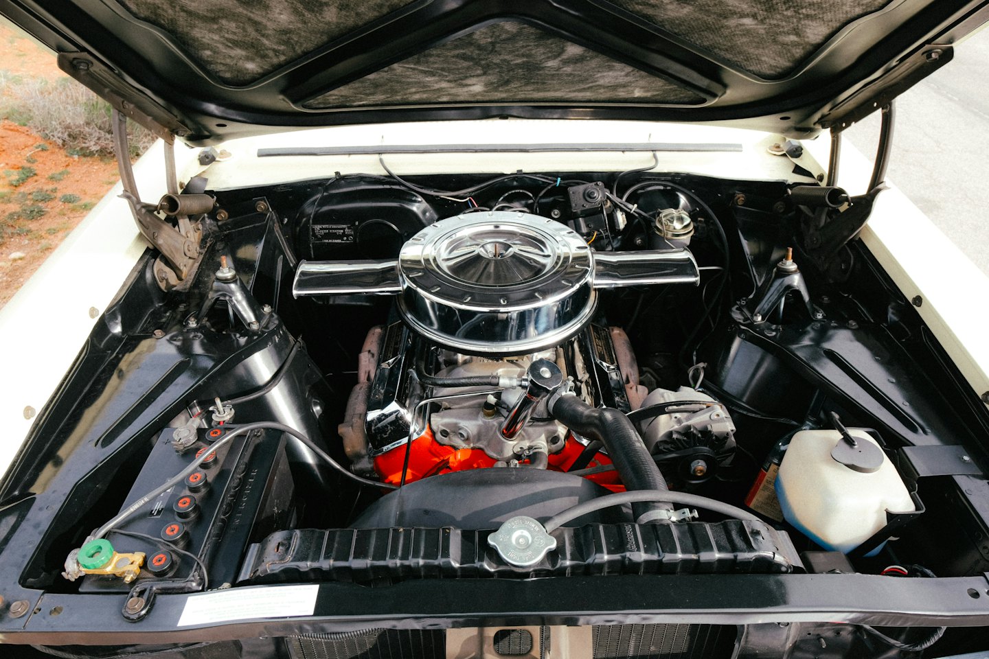 Classic car engine with a red block and chrome details.