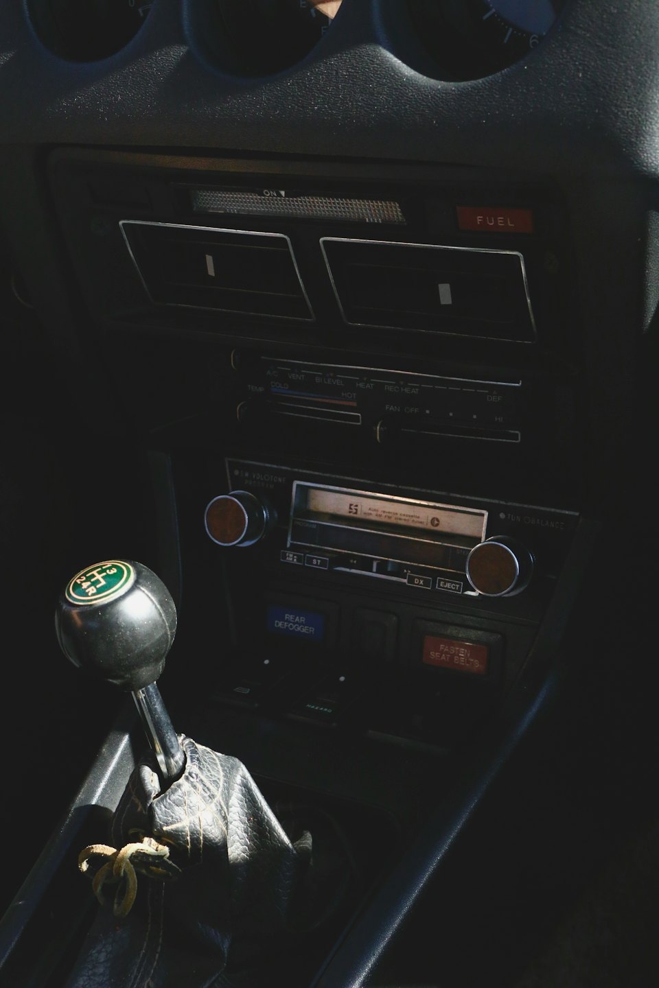 Vintage car dashboard with manual gear shift and control buttons.